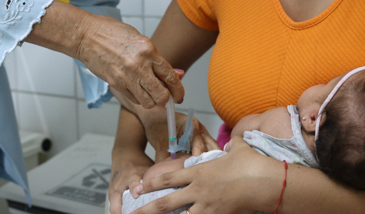 enfermeira vacina um babê no colo da mãe